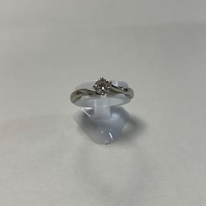 May include: A silver ring with a single round diamond set in a twisted band.