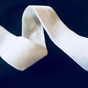 Könnte beinhalten: Weißes Samtband, ein weiches und luxuriöses Material, perfekt, um jedem Projekt einen Hauch von Eleganz zu verleihen.
