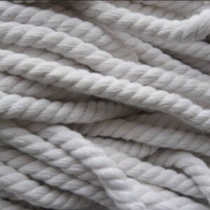May include: A close-up of a pile of thick, white cotton rope. The rope is twisted and has a soft, natural texture.