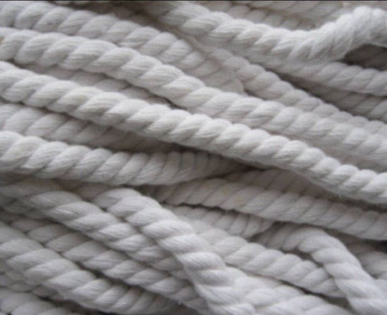 May include: A close-up of a pile of thick, white cotton rope. The rope is twisted and has a soft, natural texture.