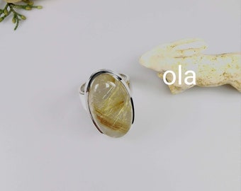 Op de afbeelding: Een zilveren ring met een heldere ovale steen met gouden insluitsels. De steen is gezet in een zilveren band.