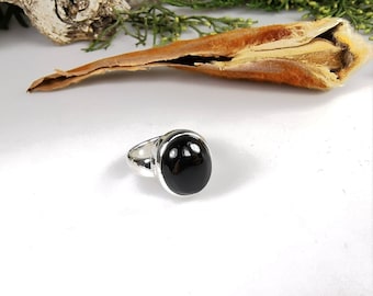Op de afbeelding: Een zilveren ring met een zwarte ovale edelsteen.