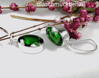 May include: A pair of silver earrings with green gemstone drops. The earrings have a simple design and are perfect for everyday wear.
