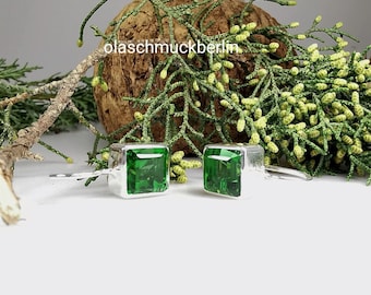 May include: A pair of silver cufflinks with square green gemstones.