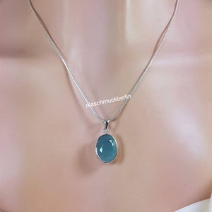 May include: A silver chain necklace with a light blue oval pendant. The pendant is set in silver and has a smooth, polished finish.