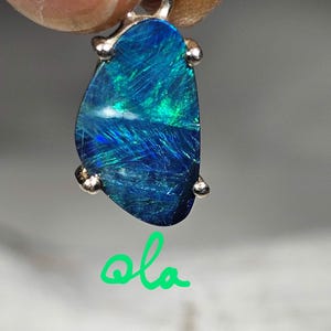 May include: A silver pendant with a blue and green opal gemstone. The opal is set in a silver bezel and has a smooth, polished finish.
