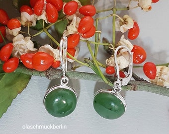 May include: A pair of silver dangle earrings with green jade stone round drops. The earrings have a hook closure.
