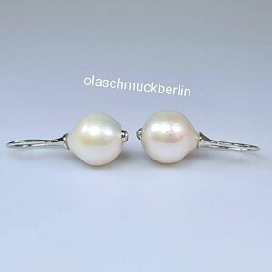 May include: A pair of silver dangle earrings with white pearl drops. The earrings are simple and elegant.