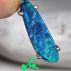 May include: A teardrop-shaped blue opal pendant with silver accents. The opal has a green and blue iridescent sheen.