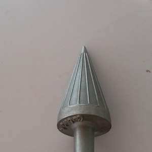 May include: A metallic, cone-shaped tool featuring a pointed tip and vertical fluted grooves along its surface. The base of the cone is wider than the shaft and displays embossed text that appears to read 'Cobalt' along the circular edge.