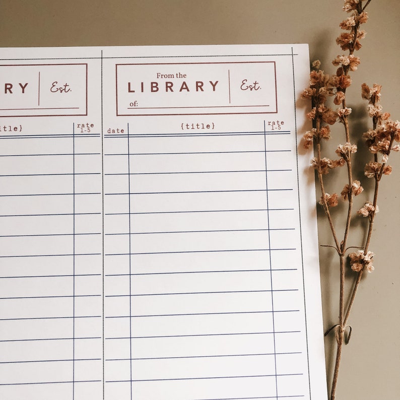 May include: A white library record sheet with blue lines and brown text. The text reads "From the LIBRARY" and "Est." The sheet has space for titles and ratings. A sprig of dried flowers is in the background.