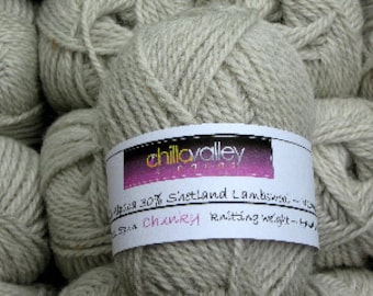 May include: Close-up of a skein of light grey chunky knitting yarn with a label that reads "chilla valley". The label also indicates the yarn is 30% alpaca and 70% Shetland lambswool. The yarn is surrounded by other skeins of the same colour.