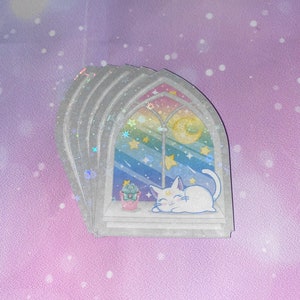 May include: A stack of four iridescent stickers featuring a white cat sleeping in a window with a rainbow and stars. The window is framed in gray and has a crescent moon in the top right corner.