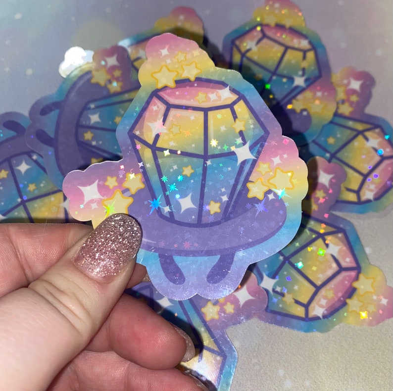 May include: A holographic sticker featuring a cartoon diamond with a rainbow gradient and surrounded by stars. The sticker has a glossy finish and is perfect for adding a touch of sparkle to any project.