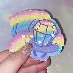 May include: A stack of rainbow holographic stickers featuring a cartoon diamond ring with stars. The stickers are iridescent and have a glittery finish.