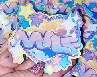 May include: A holographic sticker with a pastel rainbow background and the word "MILK" in a bubbly font. The sticker is decorated with stars and pearls.