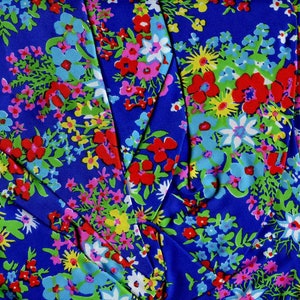 K&ouml;nnte beinhalten: Blauer Stoff mit einem bunten Blumenmuster. Der Stoff zeigt rote, rosa, gelbe, wei&szlig;e und blaue Blumen auf blauem Hintergrund.