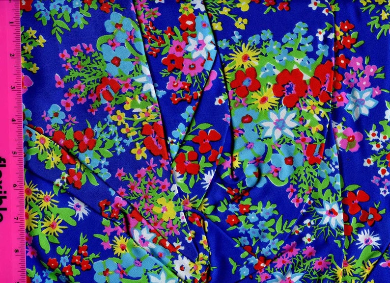 K&ouml;nnte beinhalten: Blauer Stoff mit einem bunten Blumenmuster. Der Stoff zeigt rote, rosa, gelbe, wei&szlig;e und blaue Blumen auf blauem Hintergrund.