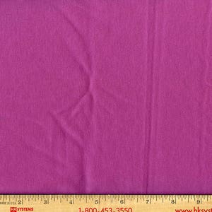 May include: A close-up of a solid purple fabric with a slight texture. The fabric is smooth and has a subtle sheen.