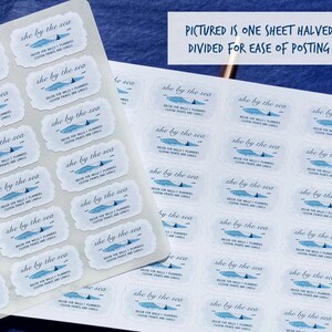 May include: Sheets of white labels with a blue and white design, featuring the text "she by the sea." The labels have a decorative border and include text about custom prints and labels. The image also includes the text: "PICTURED IS ONE SHEET HALVED. DIVIDED FOR EASE OF POSTING."