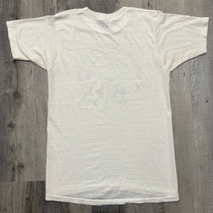 Puede incluir: Una camiseta blanca de manga corta con cuello redondo.