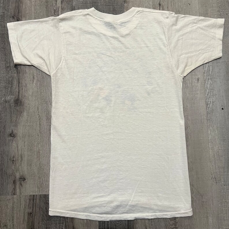 Puede incluir: Una camiseta blanca de manga corta con cuello redondo.