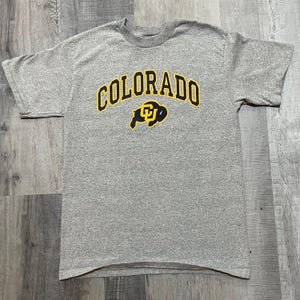 May include: Gray t-shirt with a yellow and black graphic of a buffalo and the text "COLORADO" in yellow.