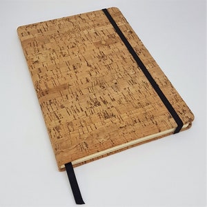 May include: A brown cork notebook with a black elastic closure. The notebook has a textured cork cover.