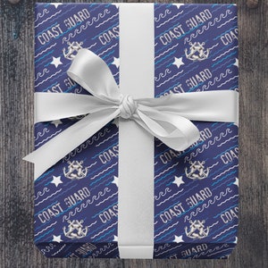 May include: A navy blue gift box with a white ribbon. The box is wrapped in paper with a repeating pattern of white waves, stars, anchors, and the text "COAST GUARD".