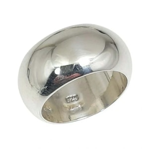 Peut inclure: Une bague dôme en argent poli avec une surface lisse et réfléchissante. L'intérieur de l'anneau présente un poinçon 925 clair, indiquant une composition en argent sterling. La bague a un profil large et arrondi avec une finition brillante.