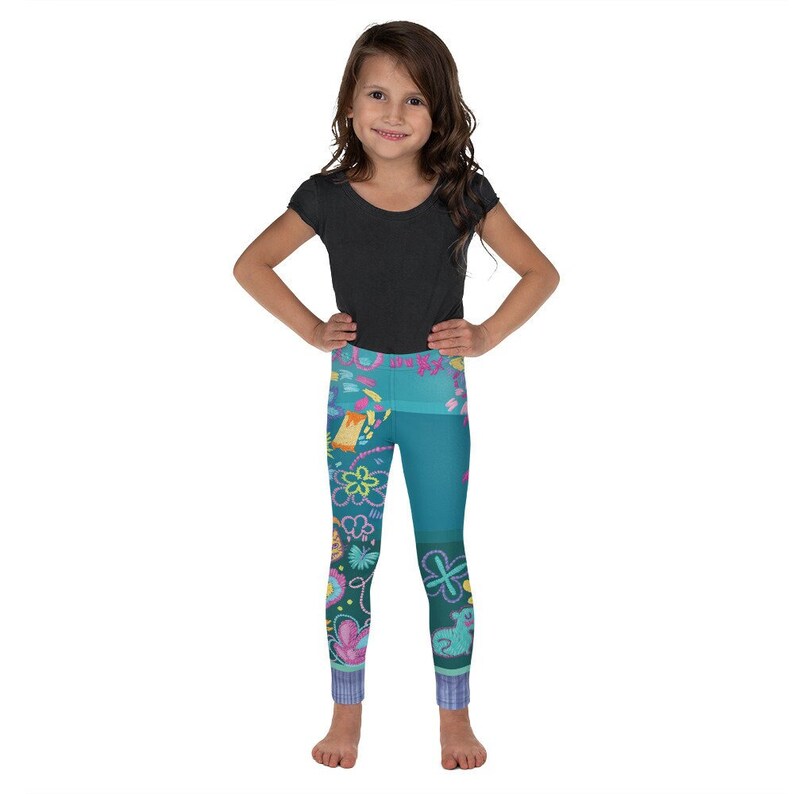 K&ouml;nnte beinhalten: Ein M&auml;dchen tr&auml;gt ein schwarzes T-Shirt mit kurzen &Auml;rmeln und eine t&uuml;rkisfarbene Leggings mit einem bunten Blumenmuster. Die Leggings hat ein t&uuml;rkisfarbenes, gr&uuml;nes und pinkfarbenes Blumendesign.