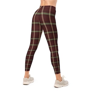 May include: Maroon leggings with a plaid pattern featuring thin stripes of light green and beige. The leggings are form-fitting and reach the ankles. The model is wearing gray sneakers.