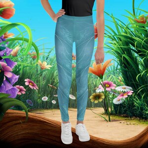 May include: A pair of blue leggings with a white and blue pattern. The leggings are worn by a person standing in a field of flowers.