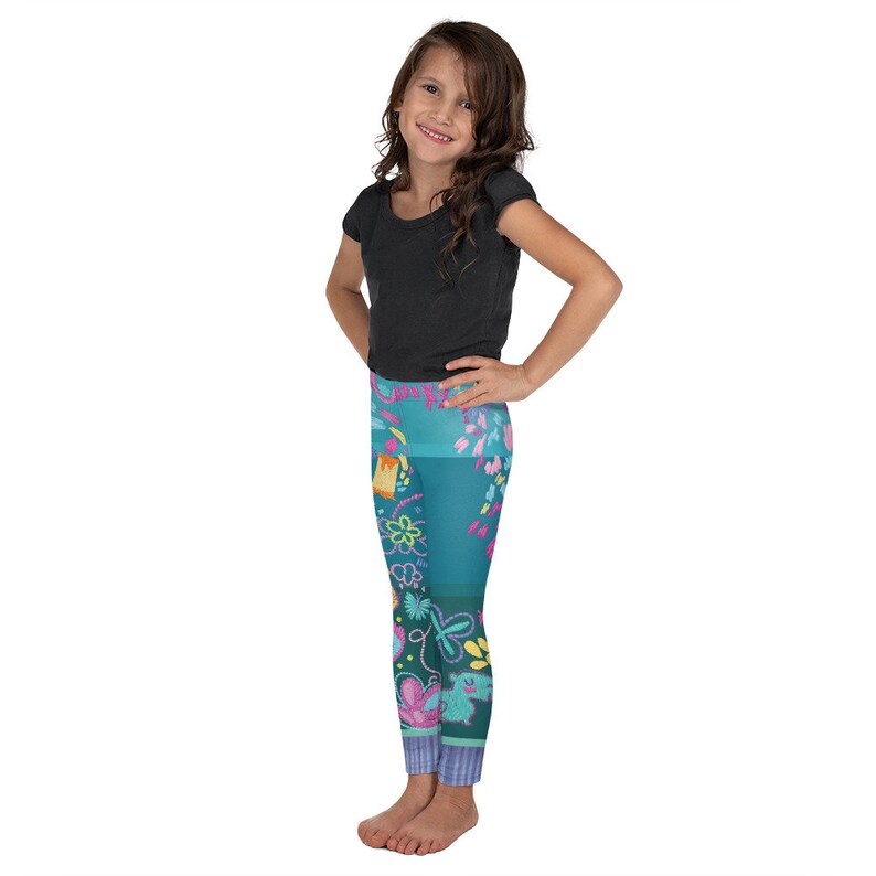 K&ouml;nnte beinhalten: Ein M&auml;dchen tr&auml;gt ein schwarzes T-Shirt mit kurzen &Auml;rmeln und eine tealfarbene Leggings mit einem bunten floralen und geometrischen Muster.