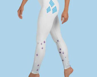May include: White leggings with a repeating pattern of purple stars and three light blue diamond shapes on the left thigh. The leggings are form-fitting and made of a stretchy material.