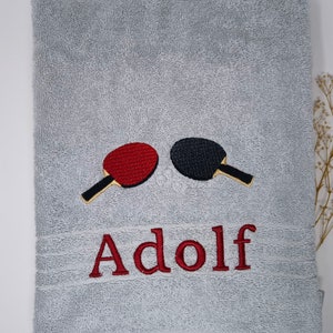 May include: Gray towel with red and black embroidered ping pong paddles and the name "Adolf" in red embroidery.