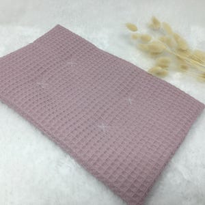 Könnte beinhalten: Ein weicher, blassrosa Waffelstoff. Der Stoff hat eine strukturierte, waffelartige Struktur.
