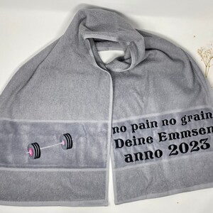 May include: Gray hooded towel with a black embroidered barbell and the text "no pain no gain Deine Emmsen anno 2023".