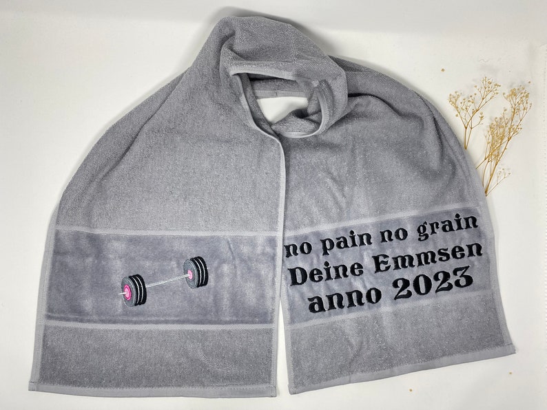 May include: Gray hooded towel with a black embroidered barbell and the text "no pain no gain Deine Emmsen anno 2023".