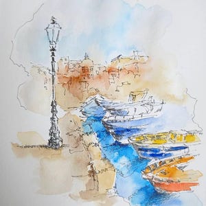 May include: Watercolor painting of a harbor scene with boats in shades of blue, yellow, and orange. A detailed black lamppost stands on the left, with buildings in the background. The word "Procida" is written in cursive at the bottom.