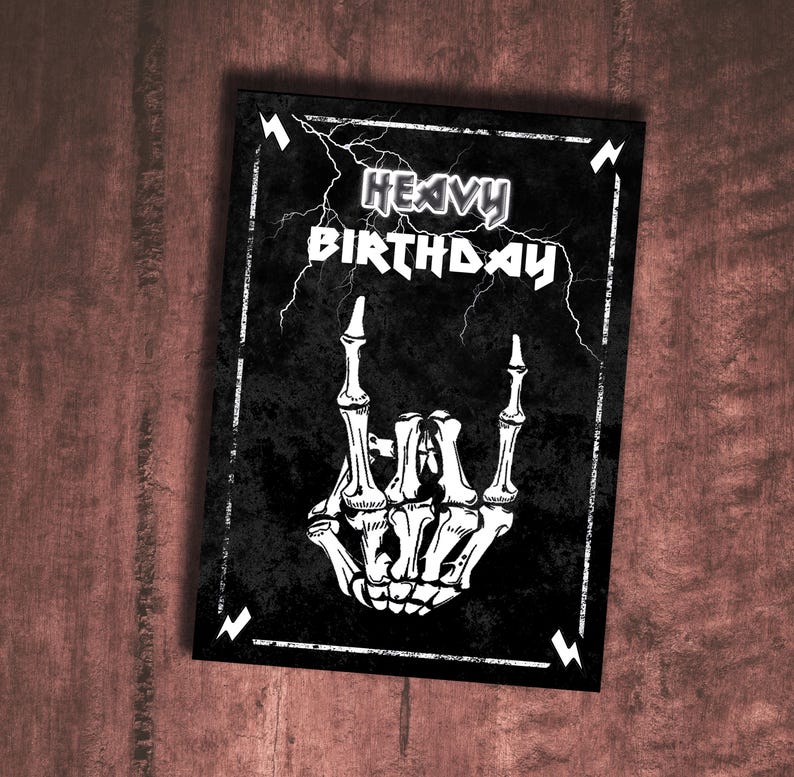 Puede incluir: Tarjeta de cumplea&ntilde;os en blanco y negro con una mano de esqueleto haciendo el gesto de la mano rock and roll. La tarjeta tiene el texto "Heavy Birthday" con rayos.