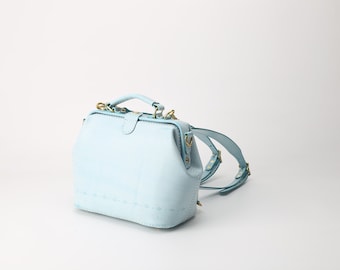 May include: A light blue leather doctor bag style backpack with gold hardware and adjustable straps.