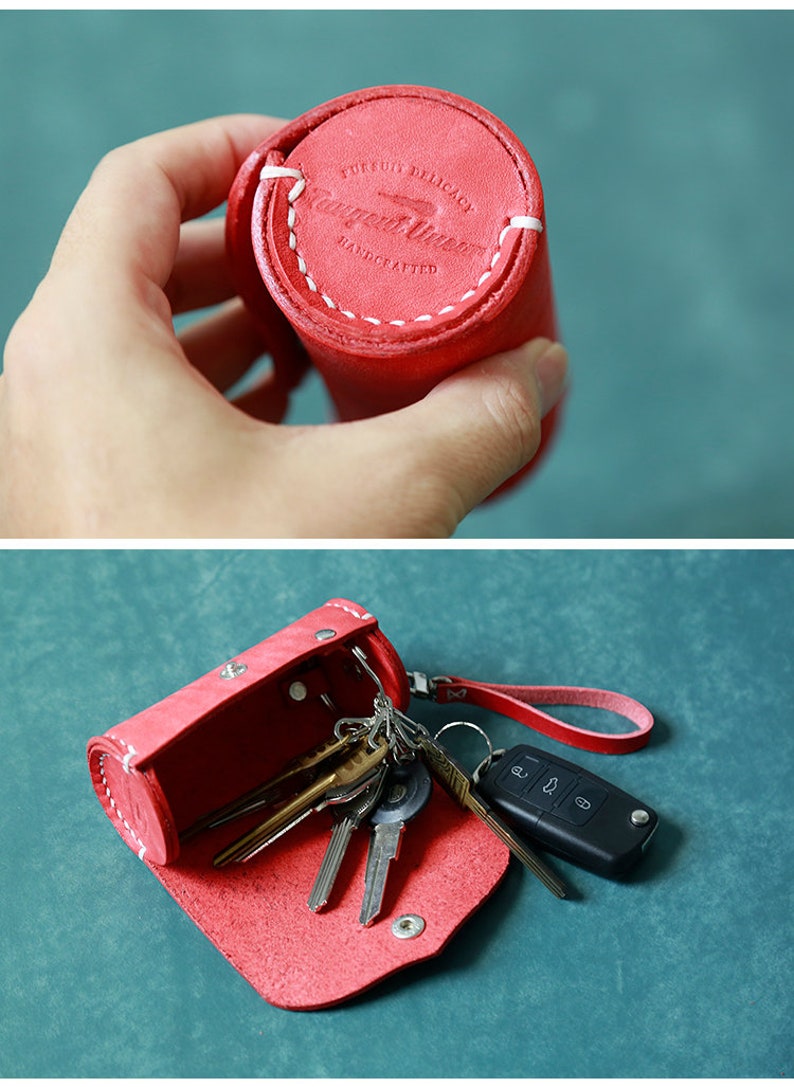 May include: Red leather key holder with a white stitched seam and the text "Pursuit Delicacy Handmade" on the top. The key holder is open and filled with keys.