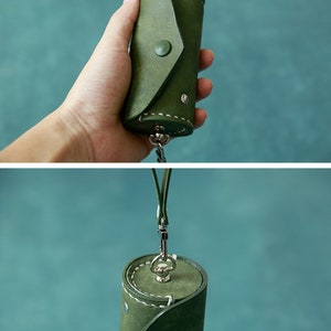 May include: A green leather key chain with a cylindrical pouch and a metal clasp. The pouch has a flap that closes with a button.