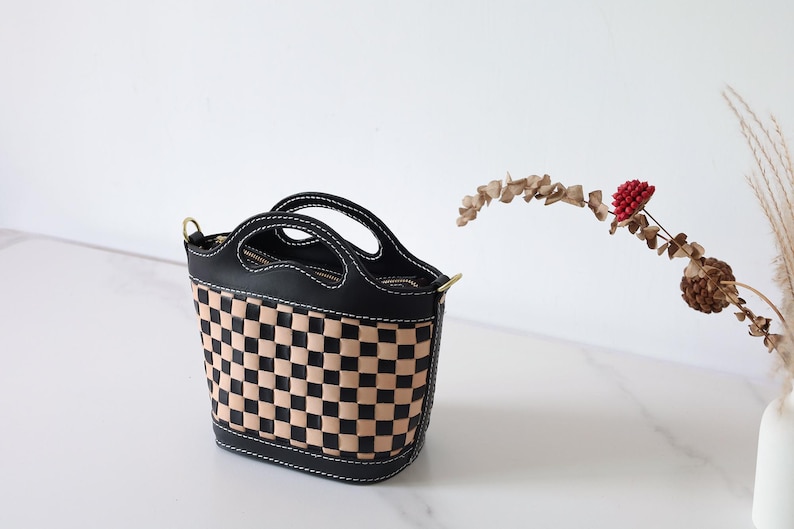 May include: A black and tan checkered leather handbag with a top handle and a shoulder strap.