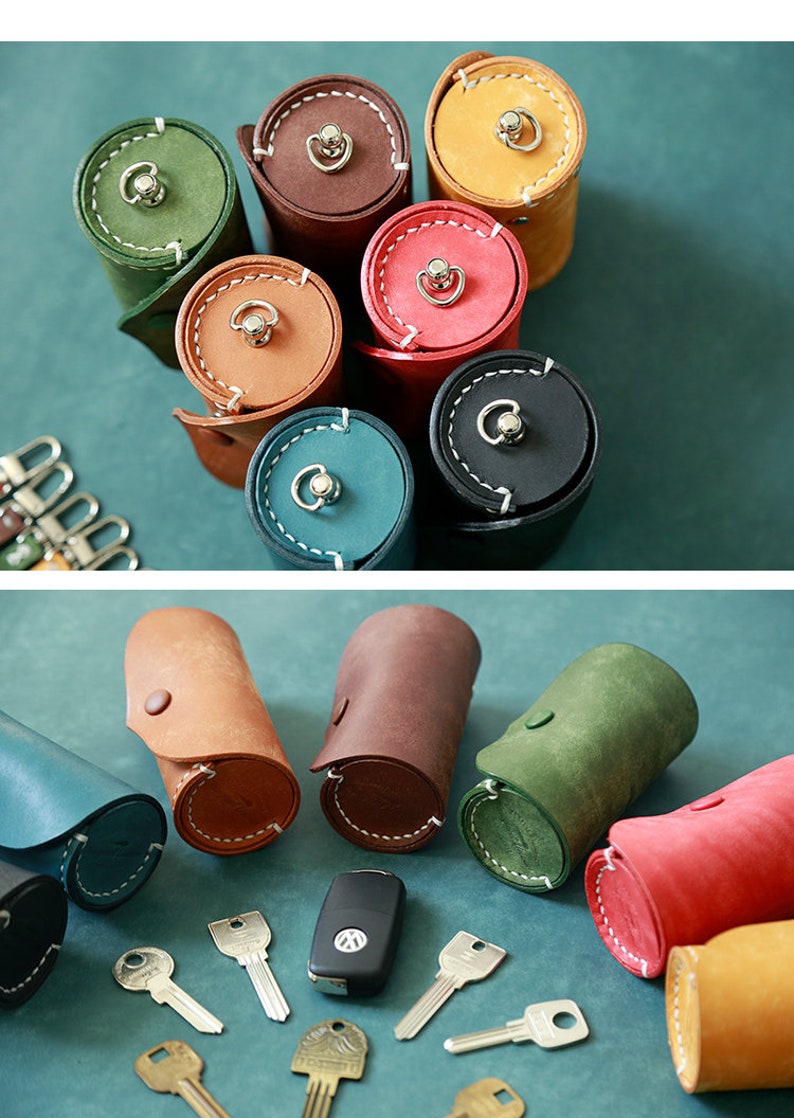 May include: An assortment of leather key holders in various colours, including brown, green, blue, red, and yellow. The key holders are rolled up and have a button closure. There are also several keys and a car key fob on a blue surface.