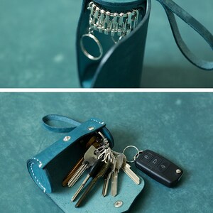 May include: A teal leather key holder with a snap closure and a loop for attaching to a belt or bag. The holder is open and filled with keys, including a car key with a remote.