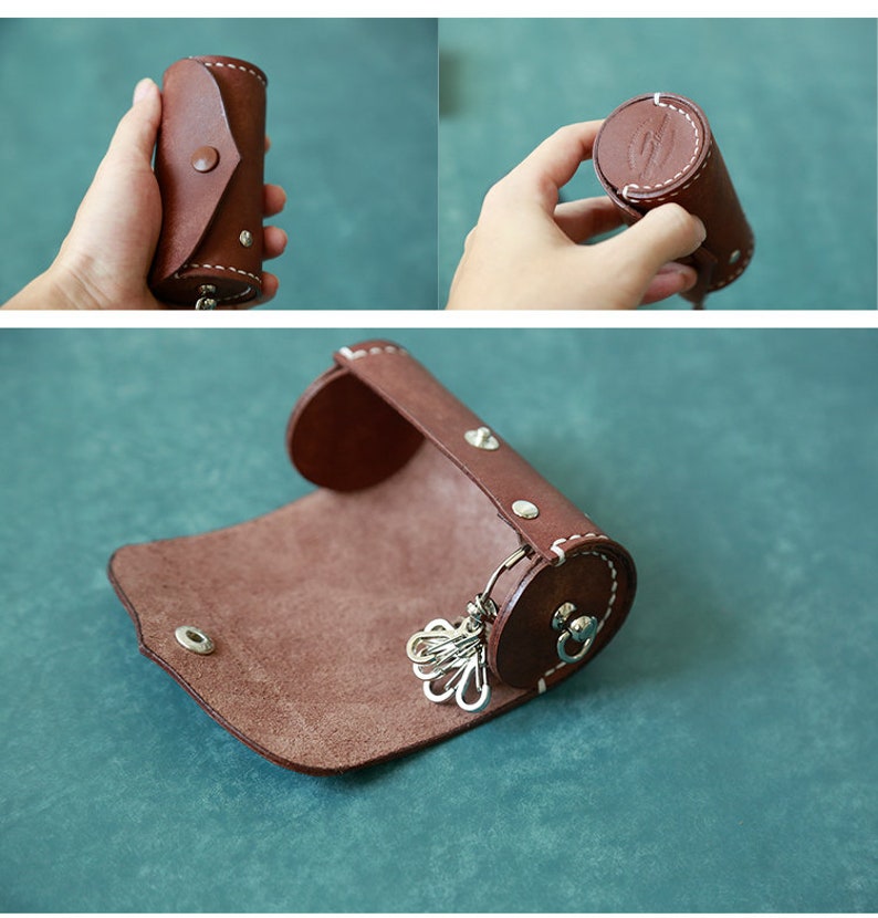 May include: A brown leather key holder with a rolled design and a metal key ring. The key holder is open and the key ring is visible.
