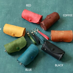 May include: Assortment of ten leather keychains in various colours, including red, yellow, green, blue, black, brown, and coffee. Each keychain features a small leather pouch with a button closure and a metal ring.