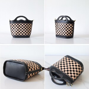 May include: A black and tan checkered leather handbag with a top handle and a shoulder strap. The bag has a rounded bottom and a flap closure.